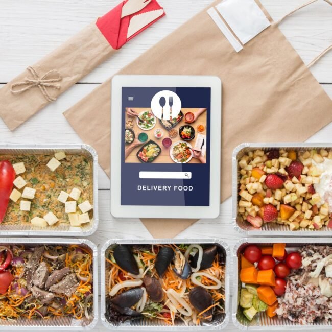 Vegetarian set in ecological packaging. Food with tofu, mussels and vegetables in containers, wooden cutlery and paper bag with tablet food delivery app and menu on screen, top view, flat lay